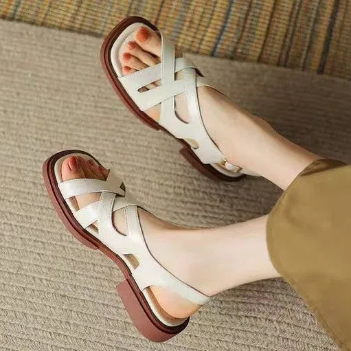 Women's black patent leather beach sandals with square toe and cross-strap design on a light background.