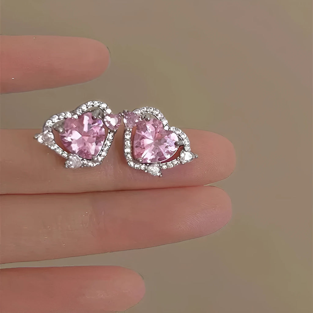 White gold colour heart-shaped stud earrings for women on a jewellery card.