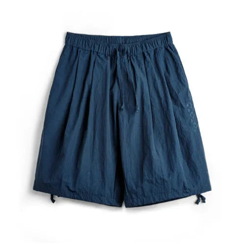 Men's Prussian Blue loose-fit nylon beach shorts with embroidered detail on a white background.