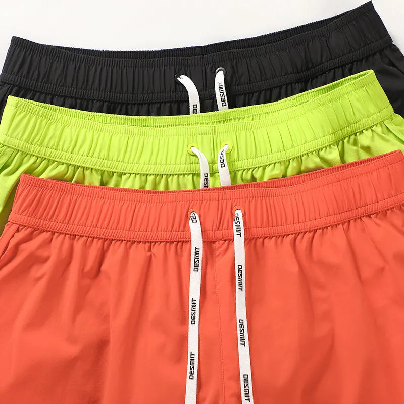 Men's loose beach surfing shorts in orange, fluorescent green, and black colors with elastic waistband
