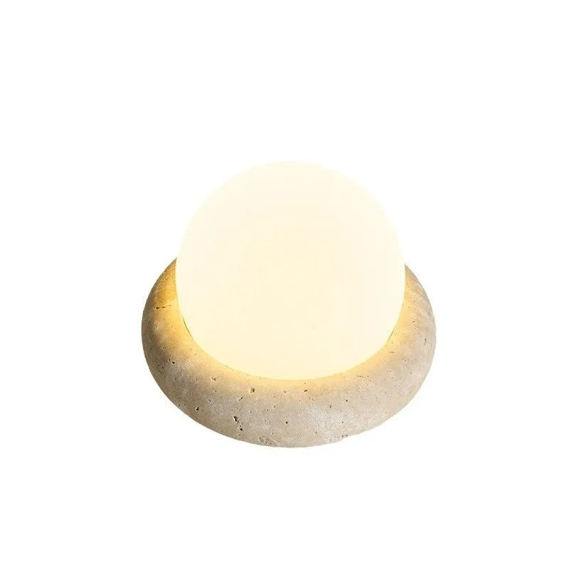 Cream coloured spherical bedside night lamp with remote control on wooden table