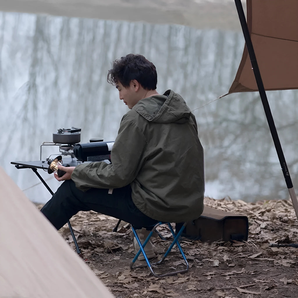 Black aluminium alloy folding stool shown in folded and unfolded positions for camping and outdoor use.