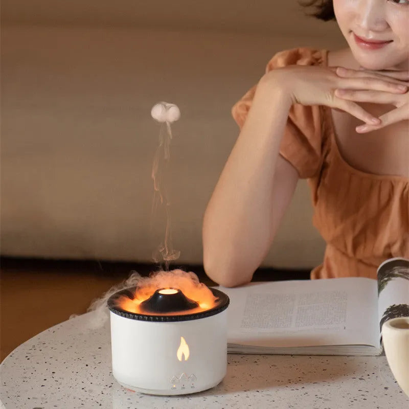 White and blue volcano-shaped tabletop humidifier emitting a mist, with mechanical controls and a UK plug adaptor.