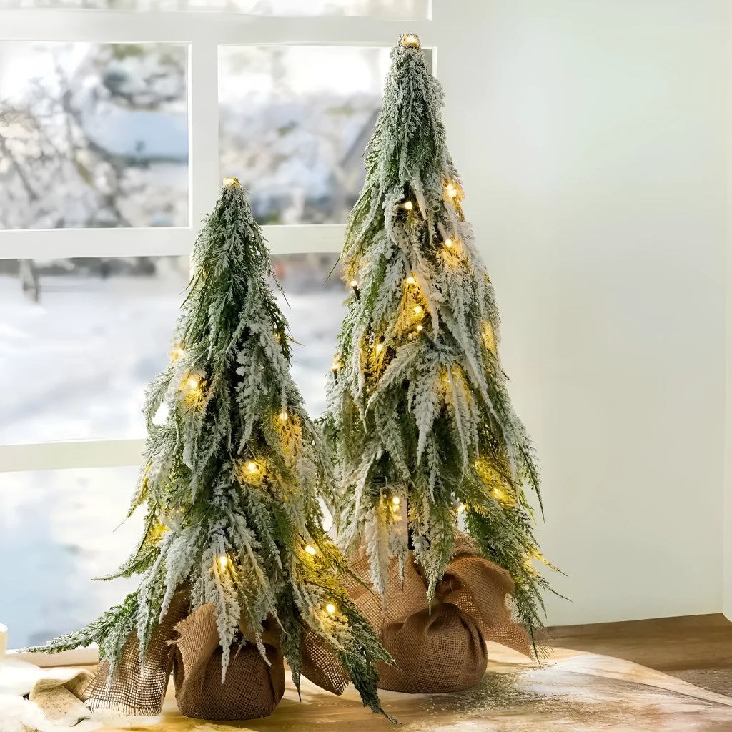 Small white 24-inch plastic Christmas tree with LED lights and simulated snow spray on desktop