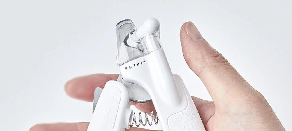 White pet nail clippers with LED light, transparent guard, and leather-like handle next to a nail file.