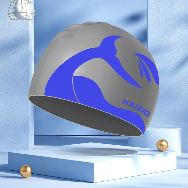 Silicone swim cap with whale tail pattern and built-in ear protectors in assorted colours.