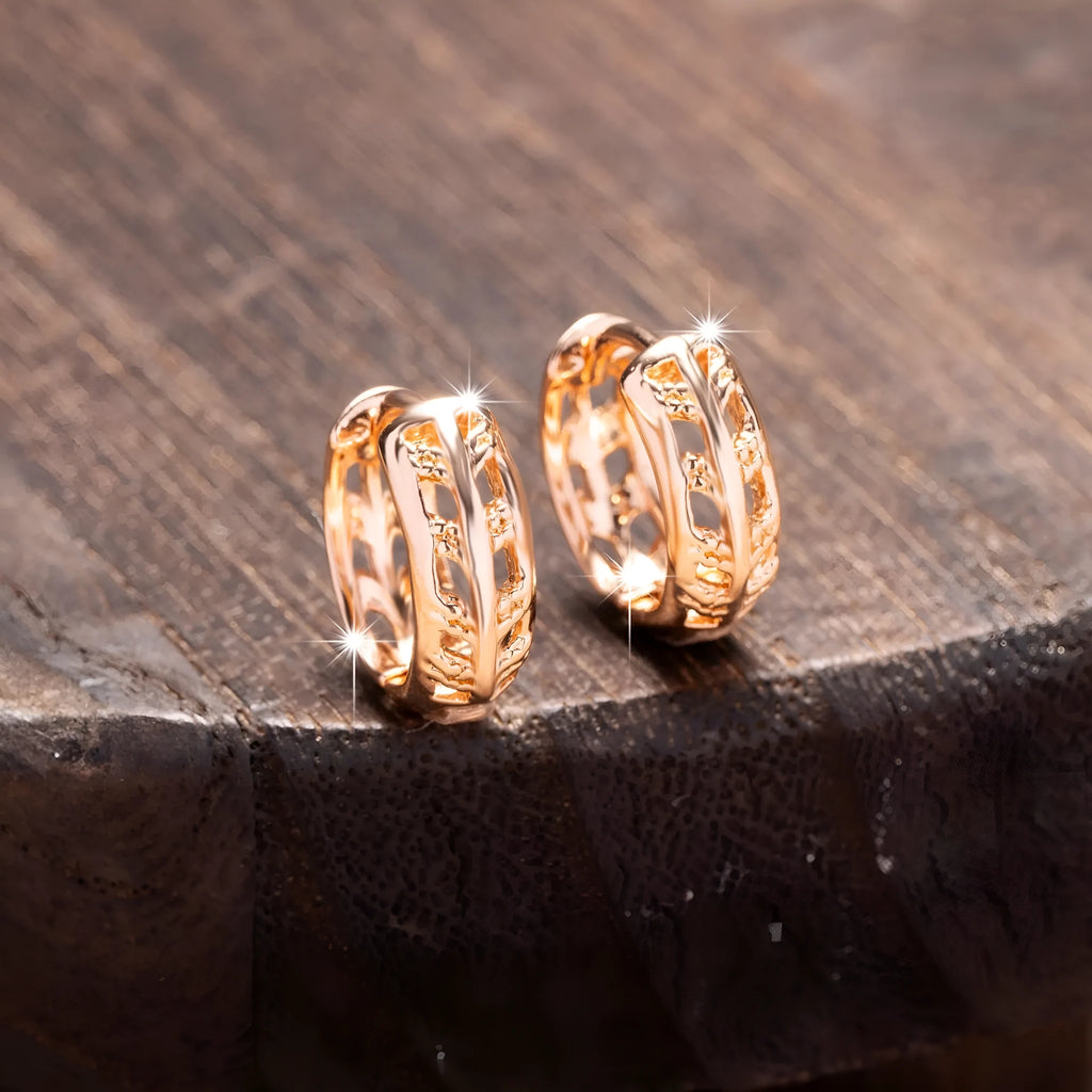 Rose gold hollowed out heart and leaf shaped copper earrings on a white background.