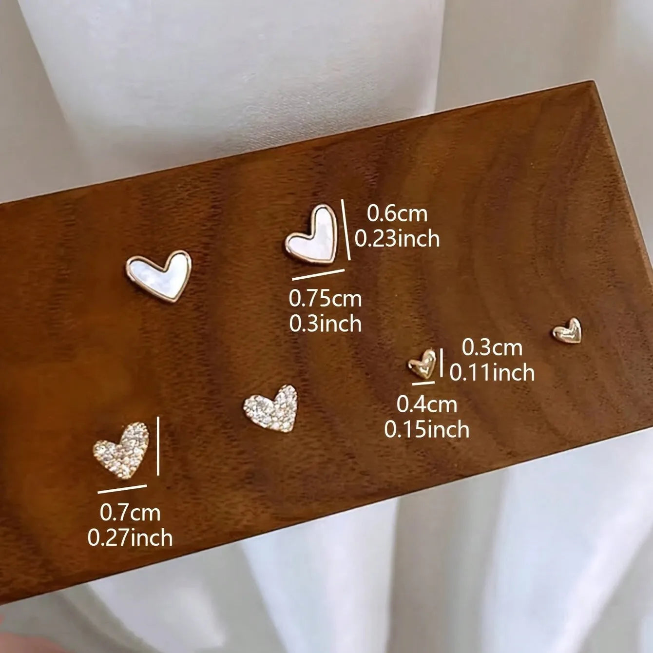 Three pairs of women's heart-shaped alloy earrings in gold, black, pink and black-white colours