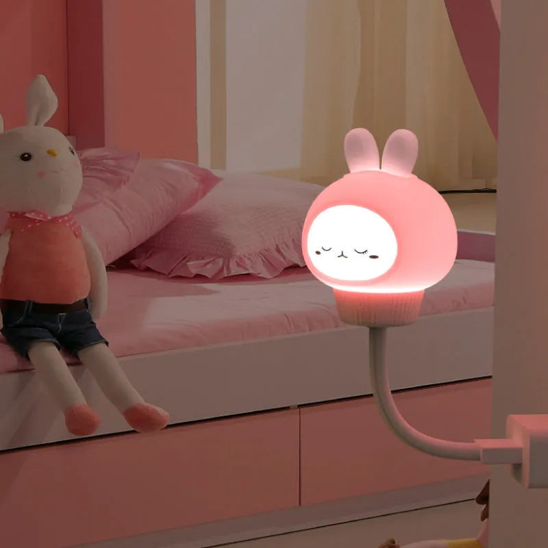 Cartoon animal USB night light with remote control on a bedside table.