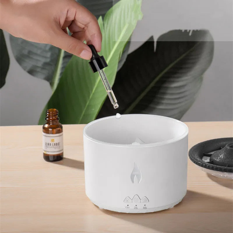 White and blue volcano-shaped tabletop humidifier emitting a mist, with mechanical controls and a UK plug adaptor.