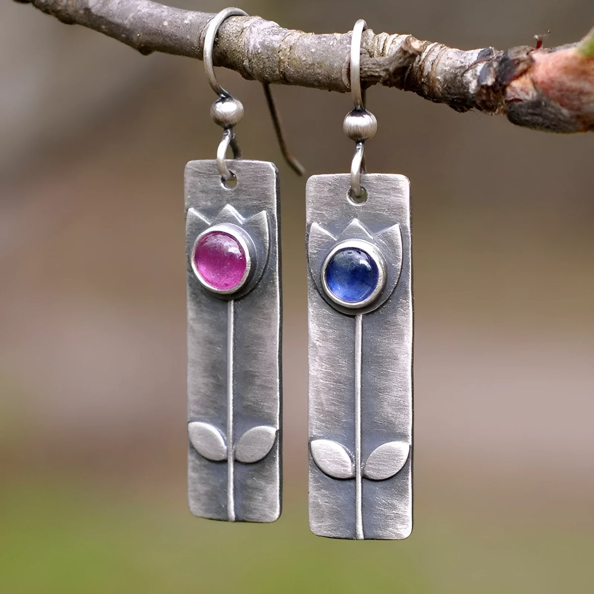 Antique finish red sapphire earrings with elliptical gemstones in a geometric design.