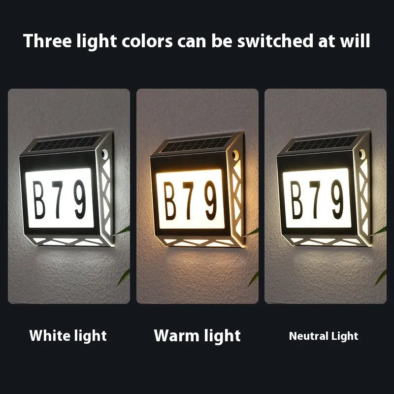 Black solar powered doorplate light with digital LED display mounted on brick wall