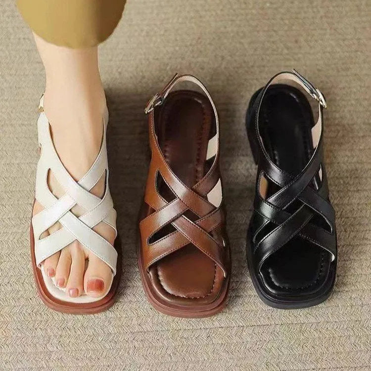 Women's black patent leather beach sandals with square toe and cross-strap design on a light background.