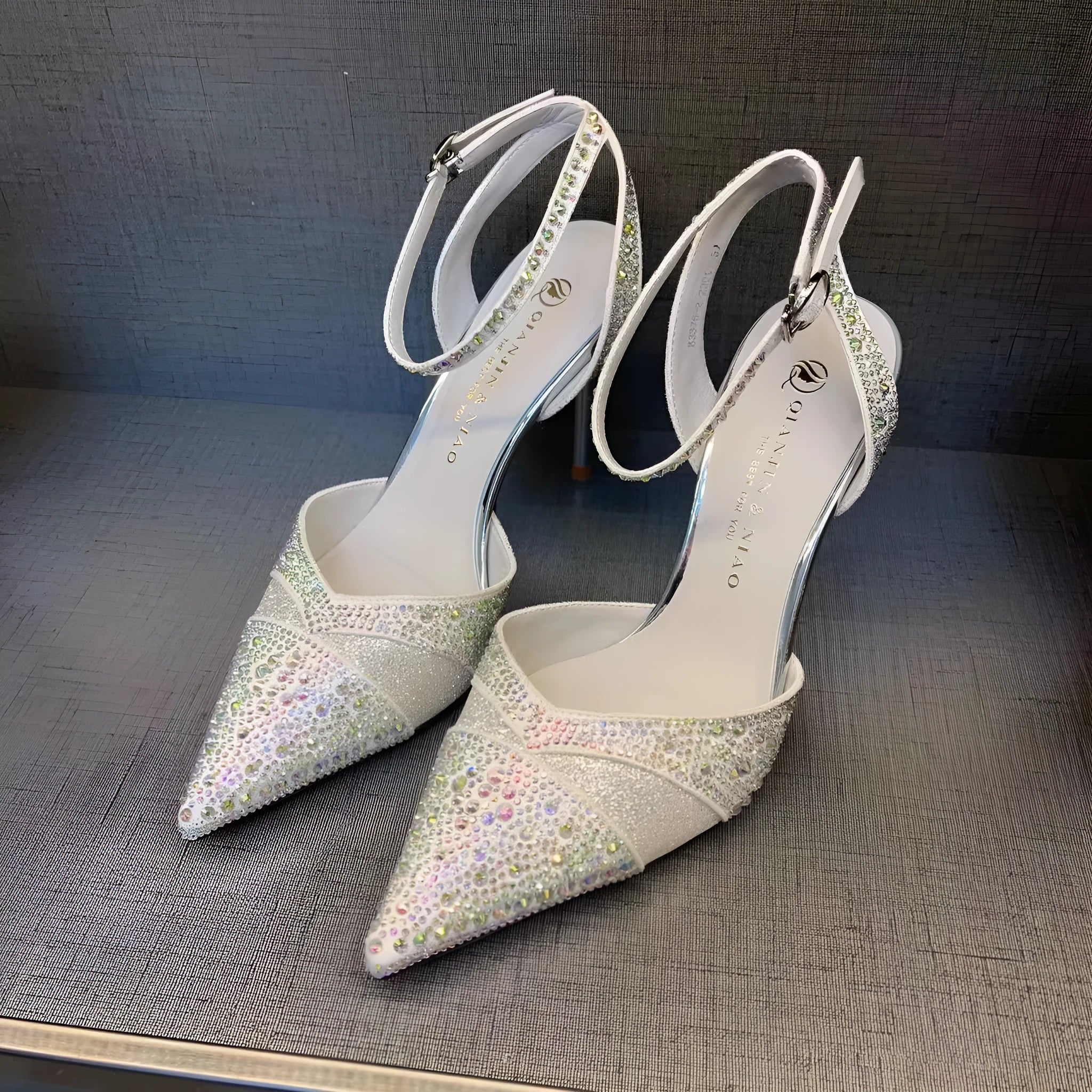 Women's silver hollow high heels with stiletto heel, pointed toe, and red sole on a plain background.