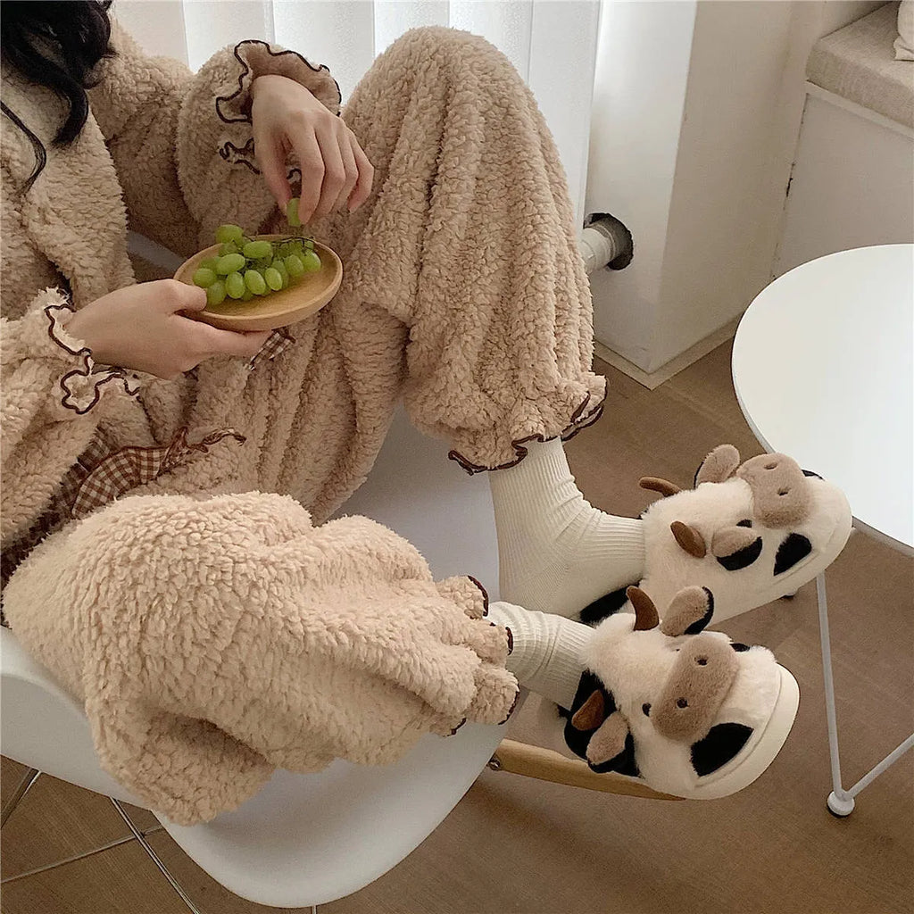White plush cow slippers for women with black spots, a smiling face, and a textured non-slip sole.