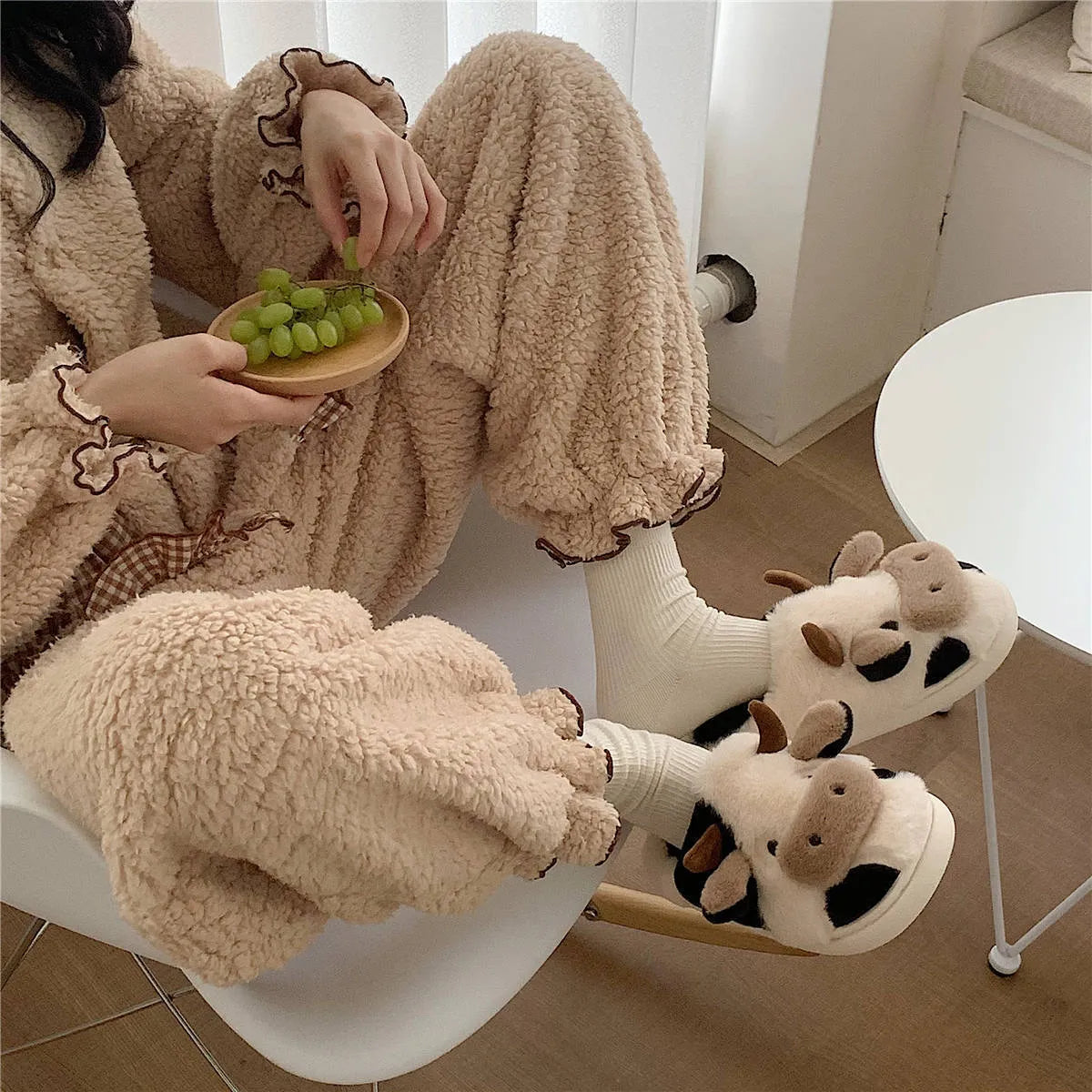 White plush cow slippers for women with black spots, a smiling face, and a textured non-slip sole.