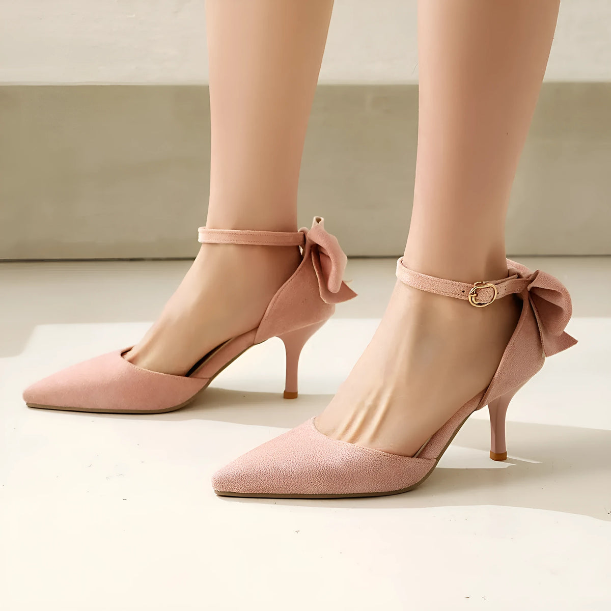 Black stiletto high heels with pointed toe and decorative bowknot detail on suede upper