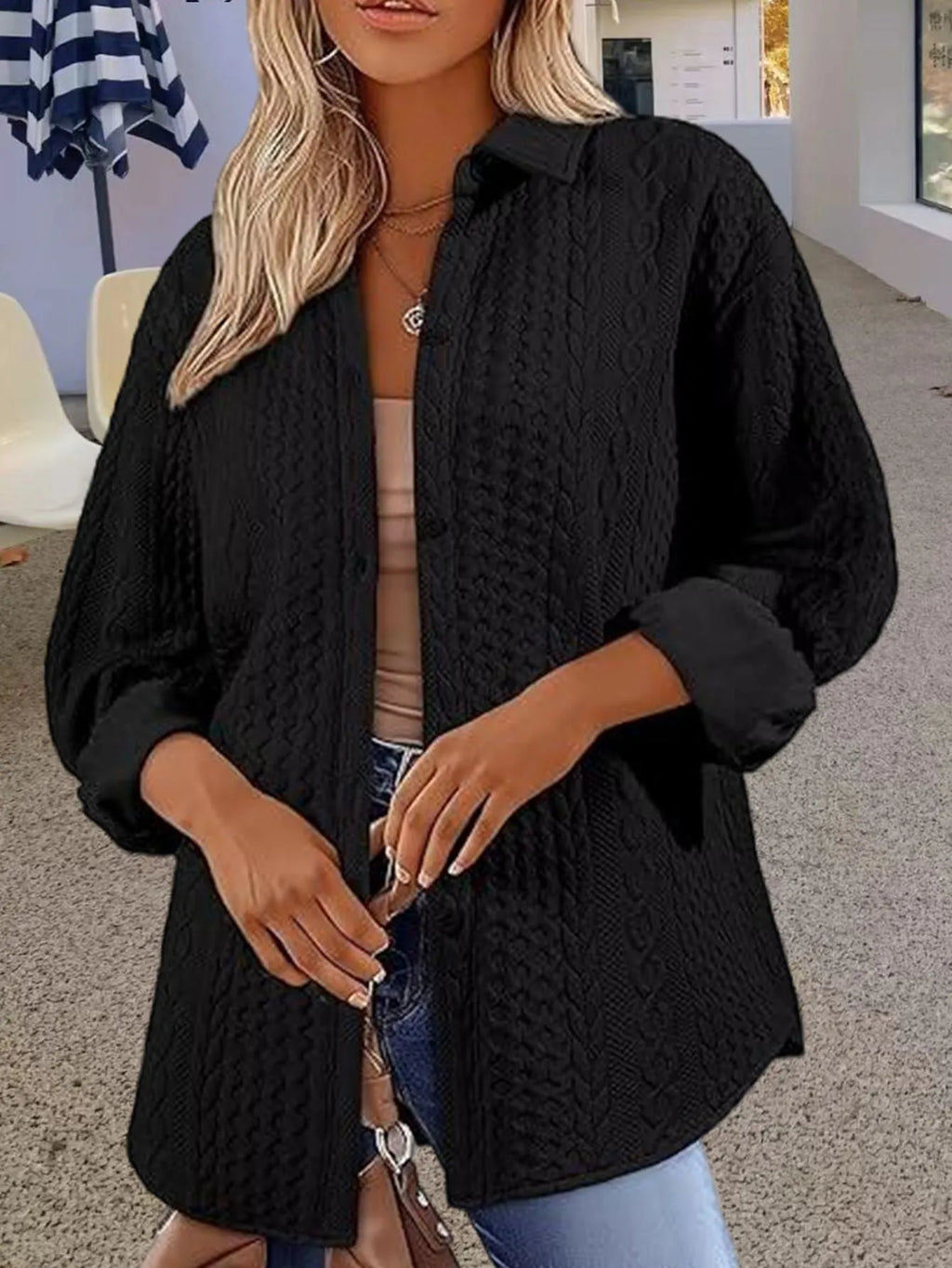 Women's solid colour knitted cardigan sweater in black, shown open over a top.