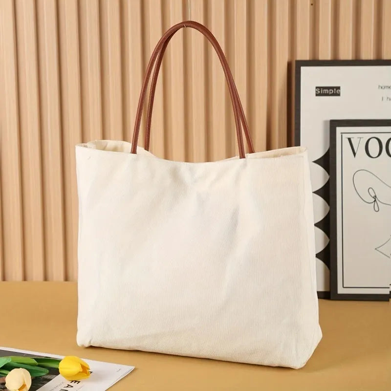 Beige white canvas tote bag with adjustable cotton handles showing reinforced bottom stitching.
