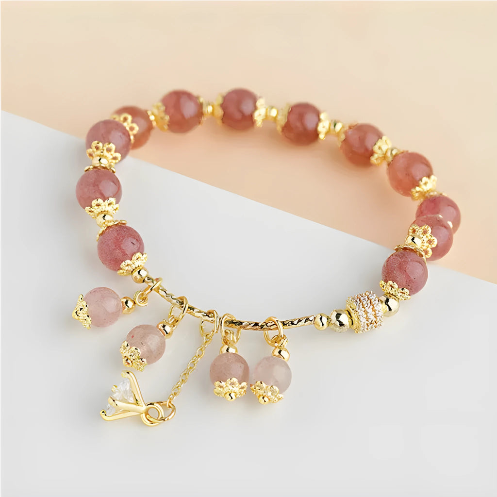 Close-up of a women's pink bracelet with a heart-shaped strawberry quartz crystal and small pearl accents on the band.