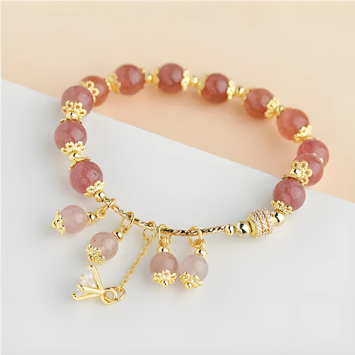 Close-up of a women's pink bracelet with a heart-shaped strawberry quartz crystal and small pearl accents on the band.