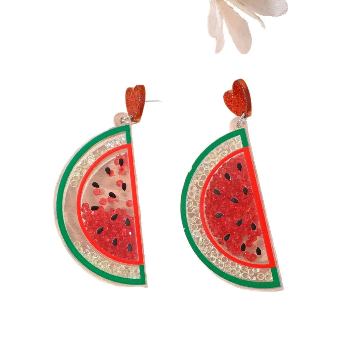 A pair of colourful acrylic earrings with a cake design next to other fruit and ice cream style earrings.